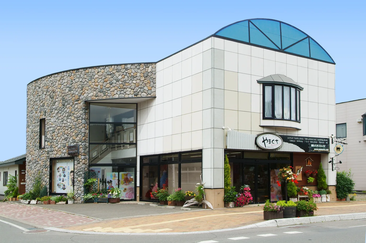 フォトスタジオ山口の外観。白い壁と石張りの丸い塔、青いガラス屋根の建物